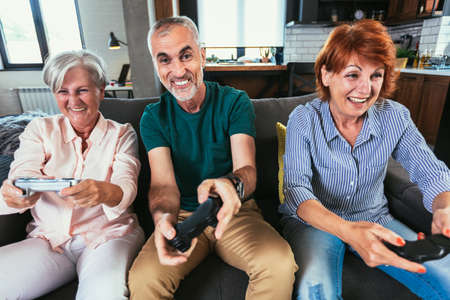 Group of middle age friends smiling happy playing video game at home.