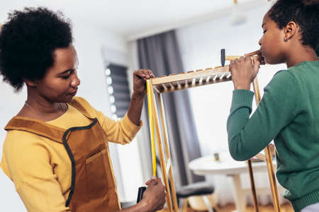 Mother and her daughter assembling furniture at home