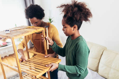 Mother and her daughter assembling furniture at home