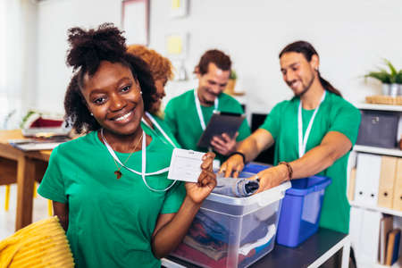 Volunteers putting clothes in donation boxes, social worker making notes charityの写真素材