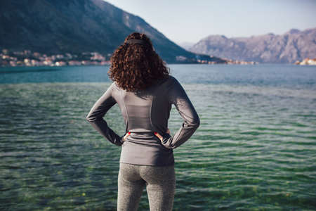 Athletic young woman with curly hair doing exercises on the beachの写真素材