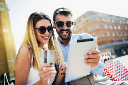 Young couple using credit card and digital tablet for online shopping outdoor.の写真素材