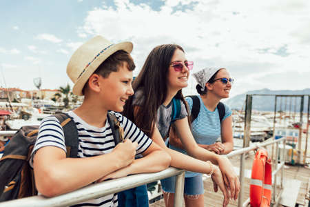 Happy mother, son and daughter walking together at seaside with luggage backpack. Travel, tourism,  family concept.の写真素材