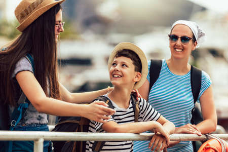 Happy mother, son and daughter walking together at seaside with luggage backpack. Travel, tourism,  family concept.の写真素材