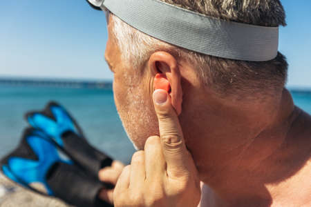 Mature man putting silicone ear plugs, surfers earplugs, swim plugsの写真素材