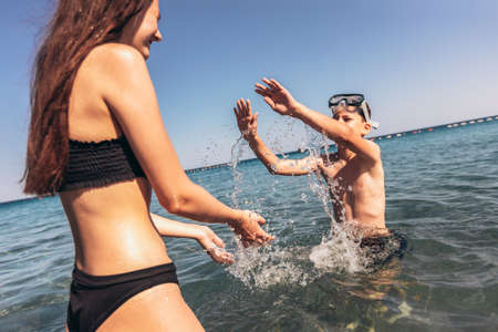 Brother and sister playing in the shore break on the beach during the hot summer vacation day.の写真素材