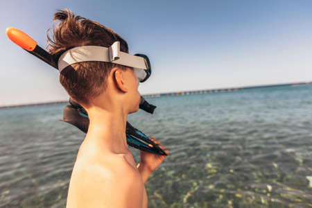 Portrait of a smiling little boy with scuba mask and snorkel by the seaの写真素材