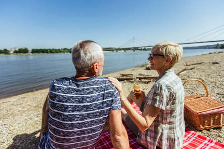 Cute senior couple enjoying picnic time on the riverside.の写真素材