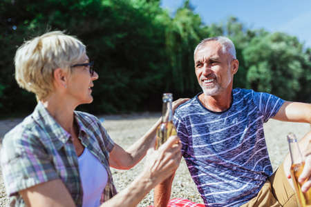 Cute senior couple enjoying picnic time on the riverside.の写真素材
