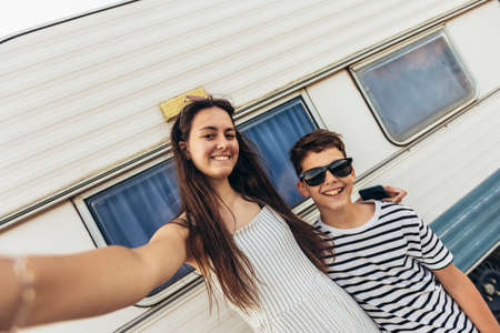 Brother and sister standing in front of a camper on a seaside holiday
