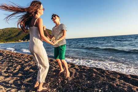 Brother and sister are having fun on the beach. Kids are dancing on the beach.の写真素材