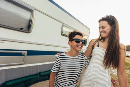 Brother and sister standing in front of a camper on a seaside holiday