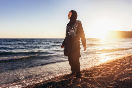 Woman in hijab standing on the beach looking at horizonの写真素材