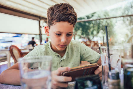 Boy addicted online games outdoors. Boy use phone and plays games.