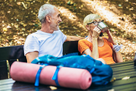 Mature couple sitting and drink coffee while resting in the forest after hiking.の写真素材