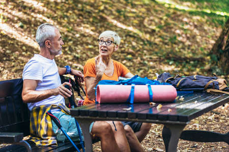 Mature couple sitting and drink coffee while resting in the forest after hiking.の写真素材