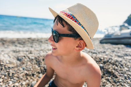 Portrait of a smiling boy on the beach with a straw hat.