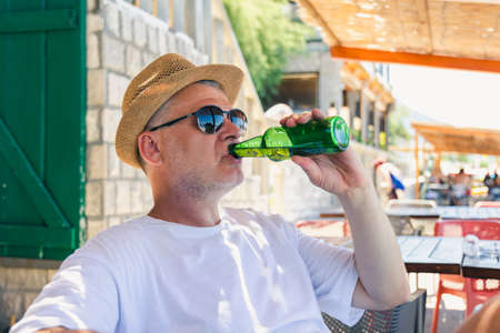 Mature handsome man enjoying beer in beach barの写真素材