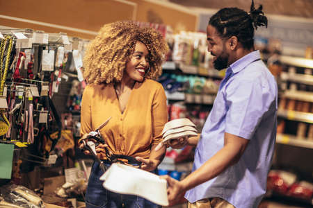 African American couple with trolley purchasing dishes in supermarket