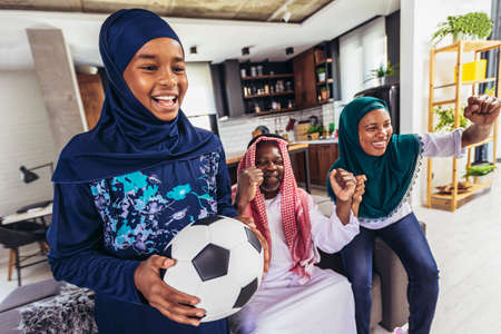 Arab man looking TV at home during a sport event with his family. Watching football game.の写真素材