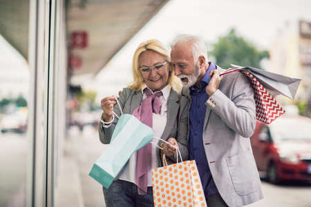 Happy senior couple walking with their shopping bags in the city.の写真素材