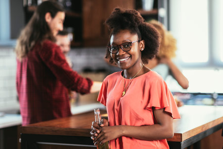 Smiling young african woman with beer standing and looking at camera.の写真素材