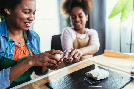 Mother and daughter spend time together and sculpting from clay at homeの写真素材
