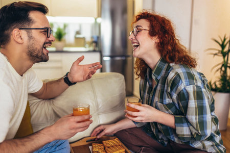 Happy young couple enjoying fresh orange juice for a breakfast at homeの写真素材
