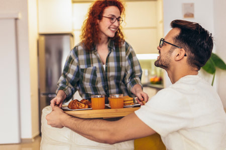 Happy young couple enjoying fresh orange juice for a breakfast at homeの写真素材