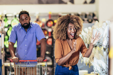 African American couple with trolley purchasing dishes in supermarketの写真素材