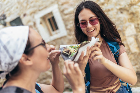 Happy mother and daughter tourists in old town enjoying pizzaの写真素材