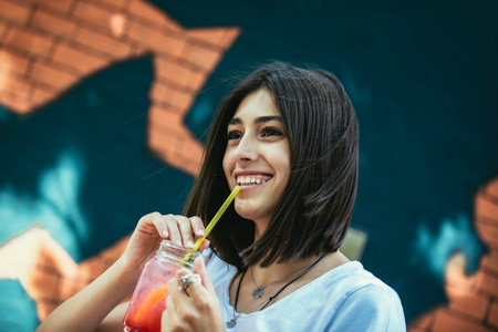Beautiful young woman drinking cocktail in outdoor cafe.