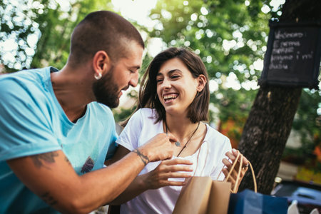 Coffee break after shopping. Couple in love drinking coffee in the cafe and sharing new purchases with each other.の写真素材