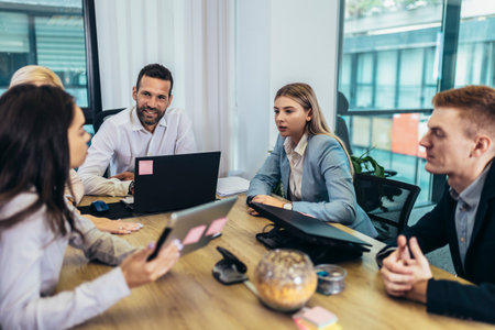 Office colleagues having discussion during meeting in conference room. Group of men and women...