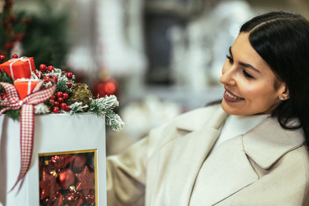 Young woman selecting christmas decorations in decorative goods shop. The girl buys Christmas decorations.の写真素材