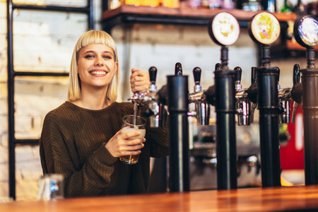 Female bartender tapping beer in bar.の写真素材
