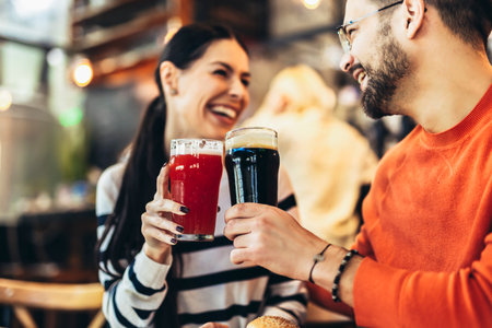 Smiling young couple at the bar with different varieties of craft beers toastingの写真素材