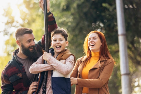 Young happy parents having fun with their boy in the park