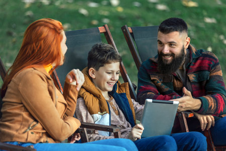 Young family enjoying time in a outdoor cafe using digital tablet.の写真素材
