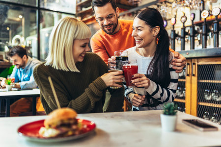 Smiling young friends drinking craft beer in pubの写真素材
