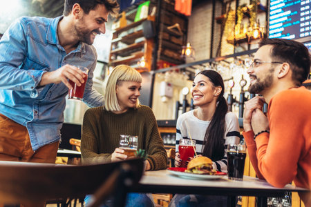 Smiling young friends drinking craft beer in pubの写真素材