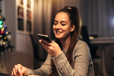 Girl using a smart phone voice recognition on line sitting on floor in the living room at homeの写真素材
