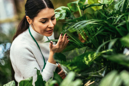 Portrait of beautiful florist working in flower shop and taking care of plantの写真素材