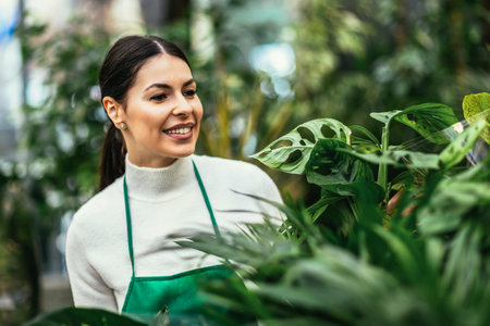 Portrait of beautiful florist working in flower shop and taking care of plantの写真素材