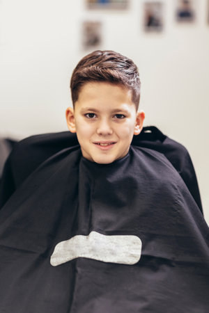 Shot of little kid covered with black cloth by hairdresserの写真素材