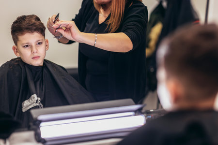 Cute young boy getting a haircut by hairdresser