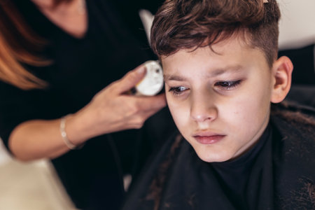 Cute young boy getting a haircut by hairdresserの写真素材