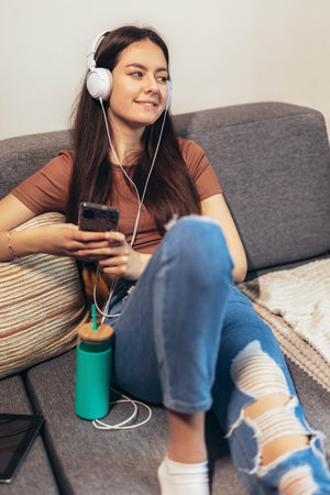 Beautiful teenager girl surfing social media on smart phone while having leisure time at her home.の写真素材