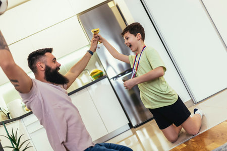 Proud father feel so excited to see his son's medals and trophies in his hand after a sports tournament.の写真素材