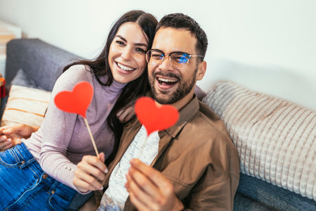 Happy smiling couple in love celebrating their relationship anniversary at home. Young couple holding a heart shape.の写真素材